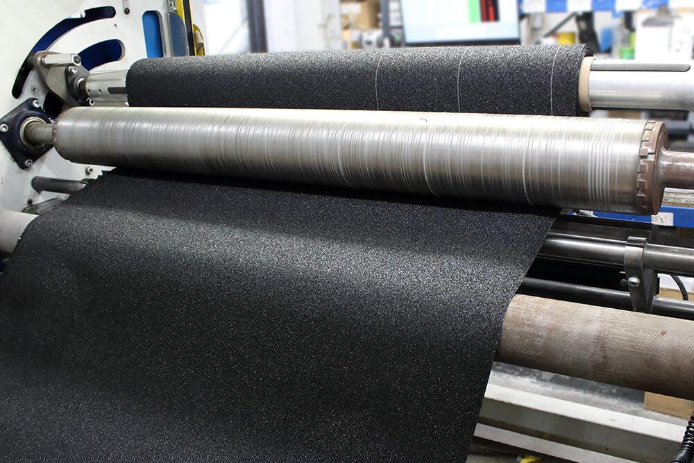 Black Anti-Slip Material being Cut on a Crush Cutter into Rolls of Wide Non Slip Tape